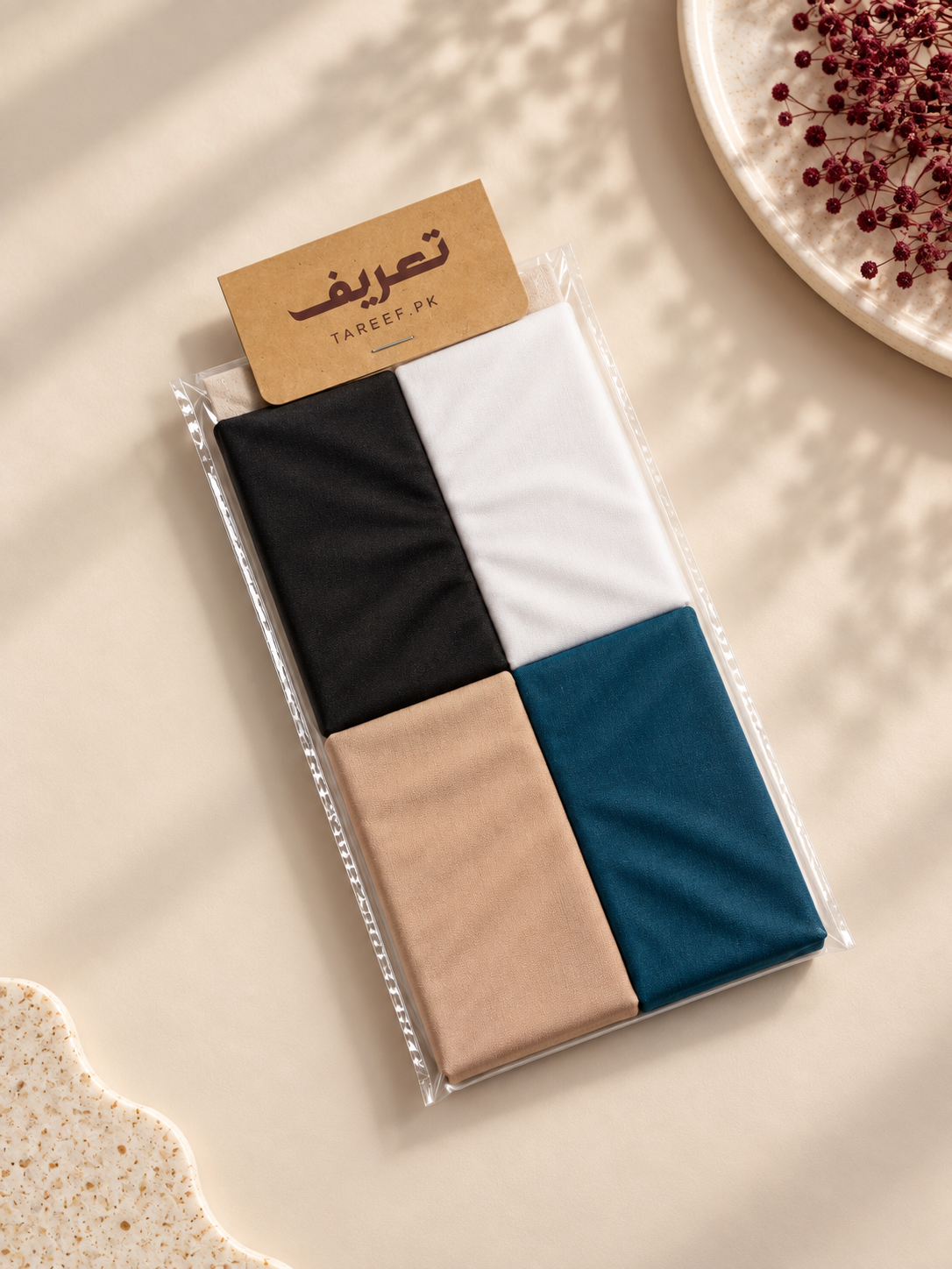 A packaged hijab tube in black, white, beige, and teal blue, sealed in a clear plastic bag with a kraft paper label reading 'TAREEF'.