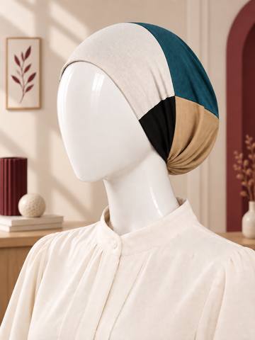 A color-blocked hijab tube displayed on a white mannequin head, styled in a warm, softly lit interior setting.