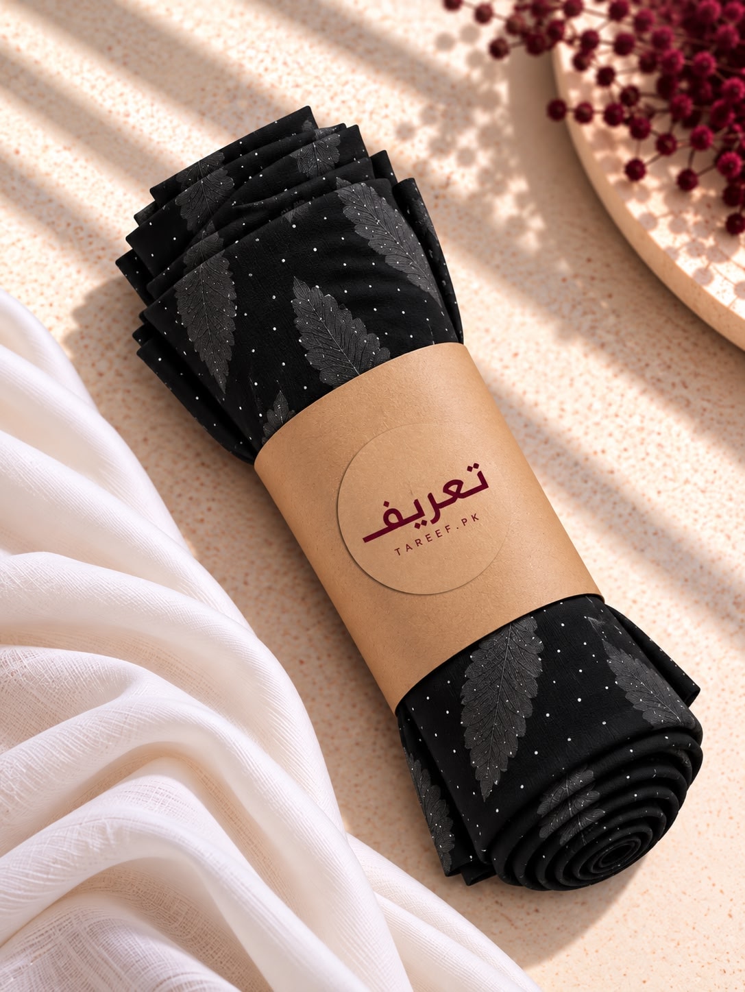 A black hijab with a subtle leaf pattern and tiny silver glitter dots, draped on a white mannequin torso in a warm, sunlit interior setting.