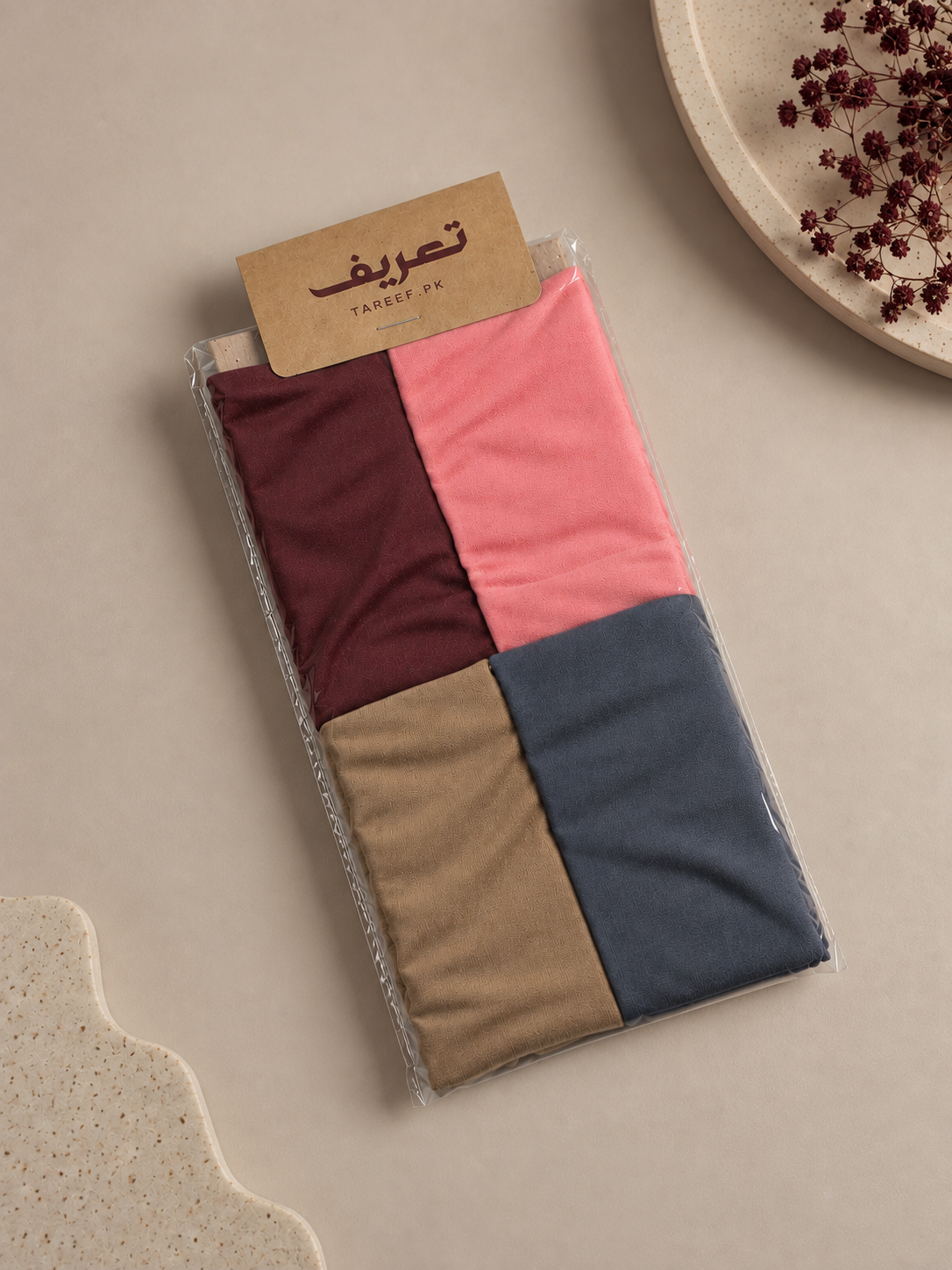 A color-blocked hijab tube displayed on a white mannequin head, styled with a cream-colored blouse in a warm, softly lit interior setting.