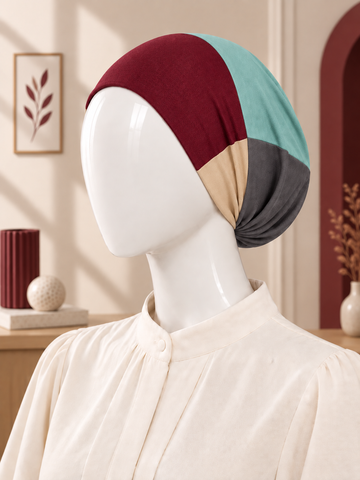 A color-blocked hijab tube displayed on a white mannequin head wearing a cream blouse. The hijab tube features four color panels: burgundy, light teal, beige, and dark gray.